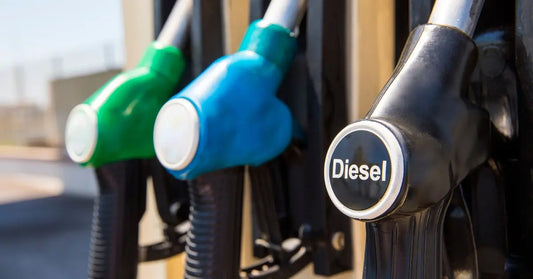 Three nozzles hooked into a fuel pump station. There is a green one, a blue one, and a black one that says "diesel."