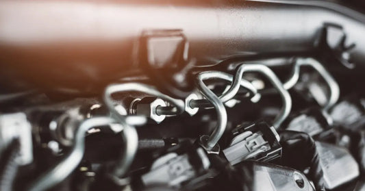A diesel engine displays curved metal fuel lines and electrical connectors across a tightly packed engine bay.